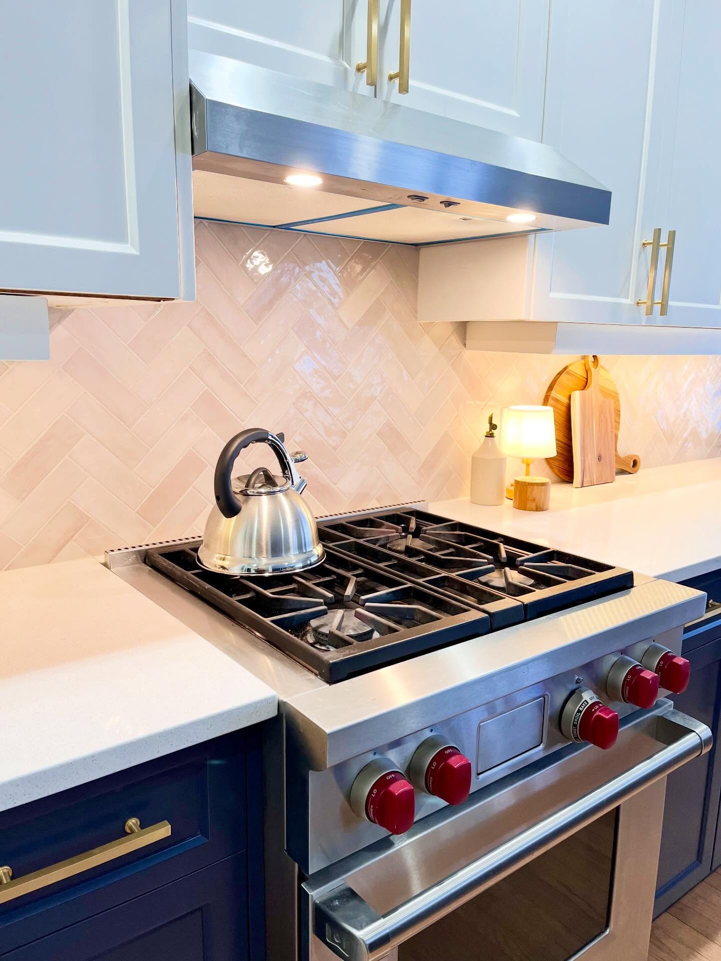 Closer view of Project Lily herringbone tile, navy drawers, brass hardware, and the Wolf range