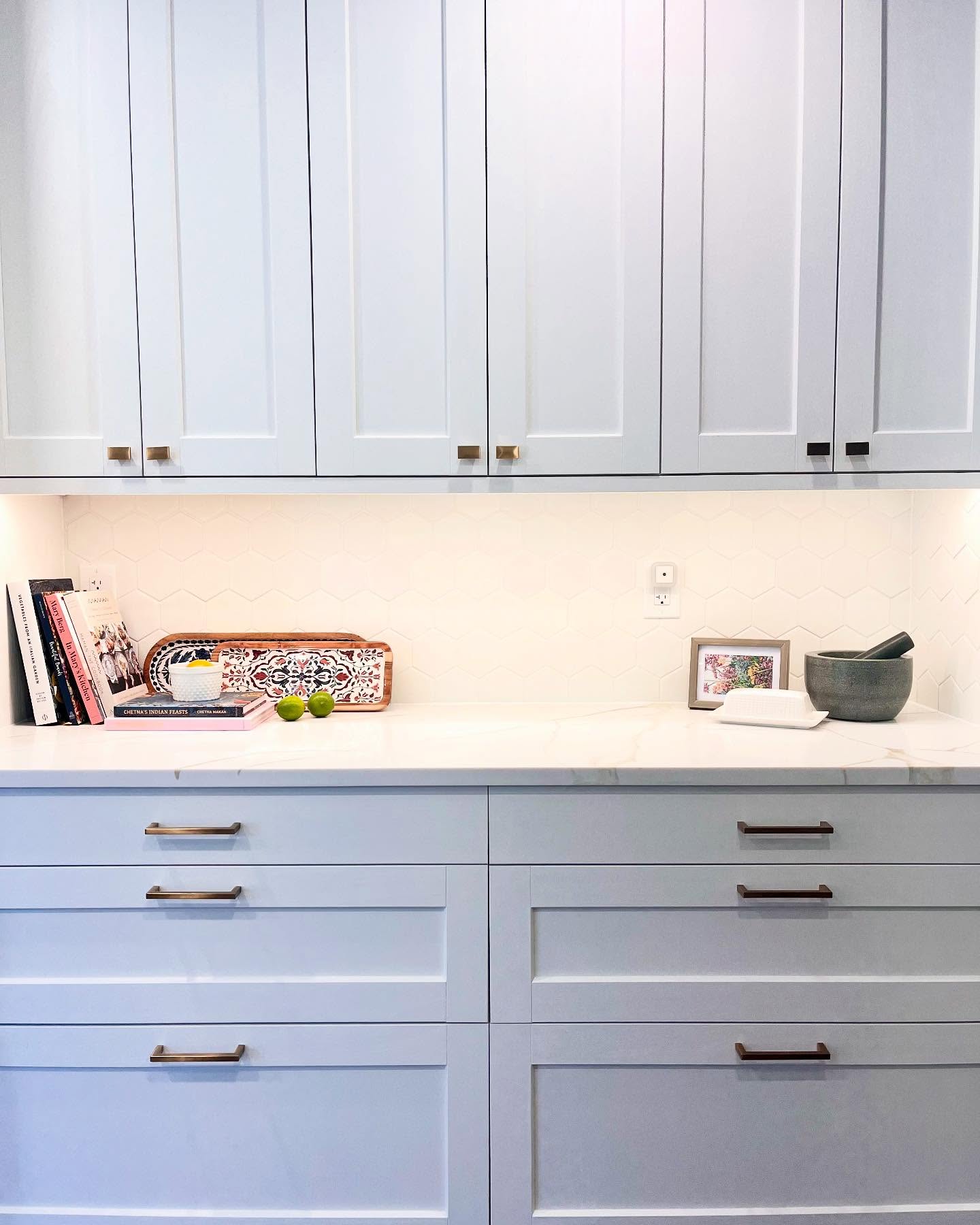 Project Daisy counter styling against white hexagon tile, pale cabinets, and brass hardware