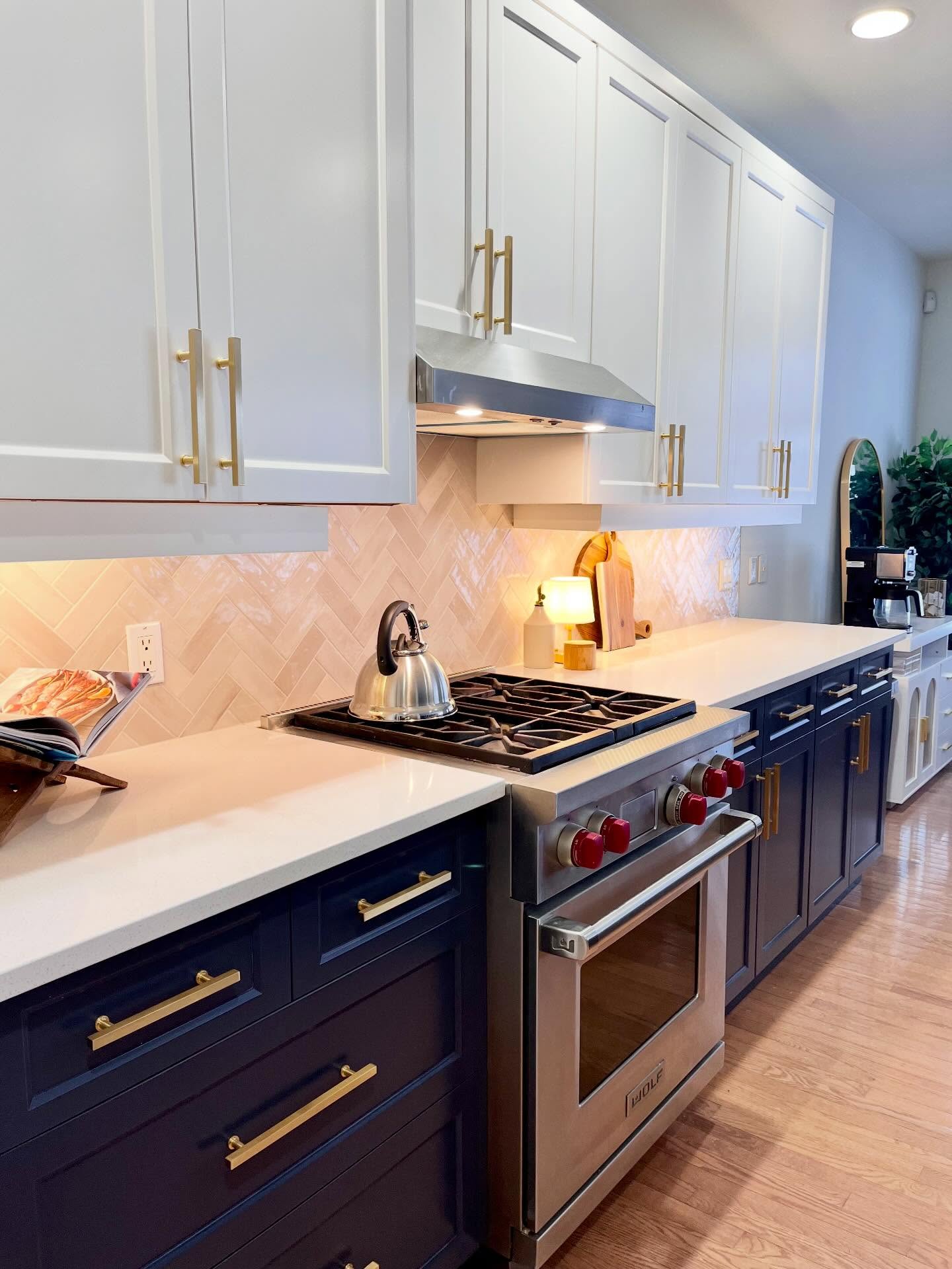 Angled view of the finished Project Lily cooking wall with navy lowers, cream herringbone tile, and a Wolf range