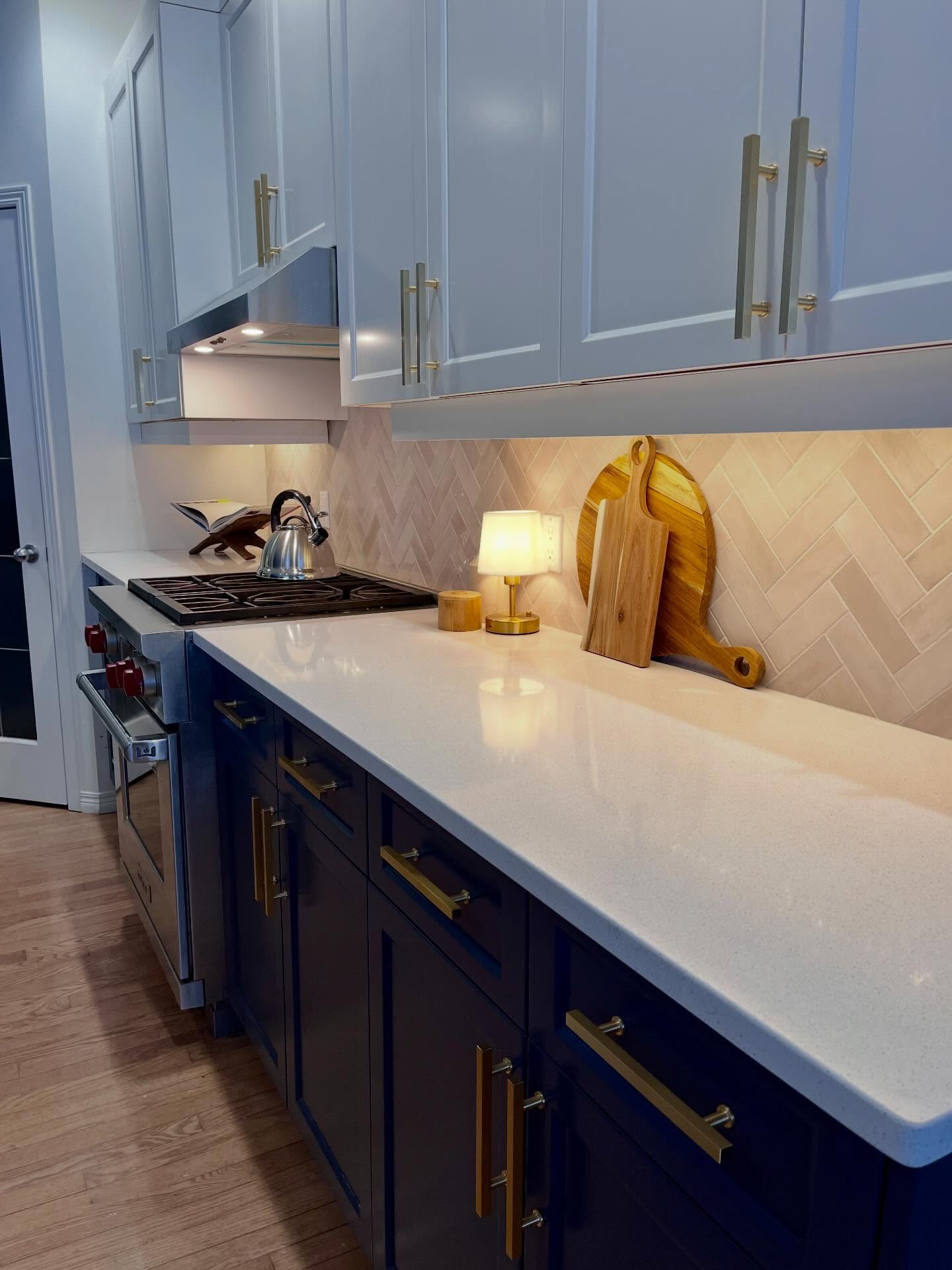 Project Lily counter run with cream herringbone tile, white counter, navy bases, and brass pulls