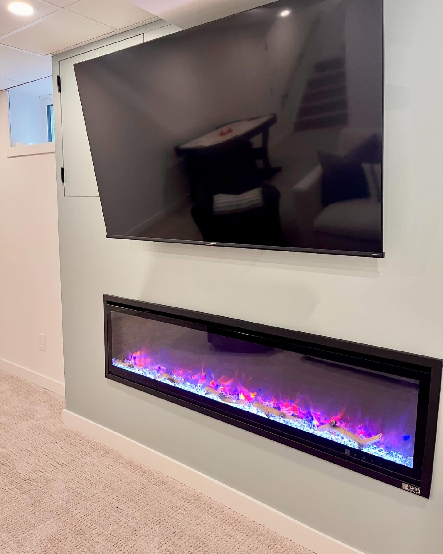 Closer view of the sage accent wall, television, and linear electric fireplace