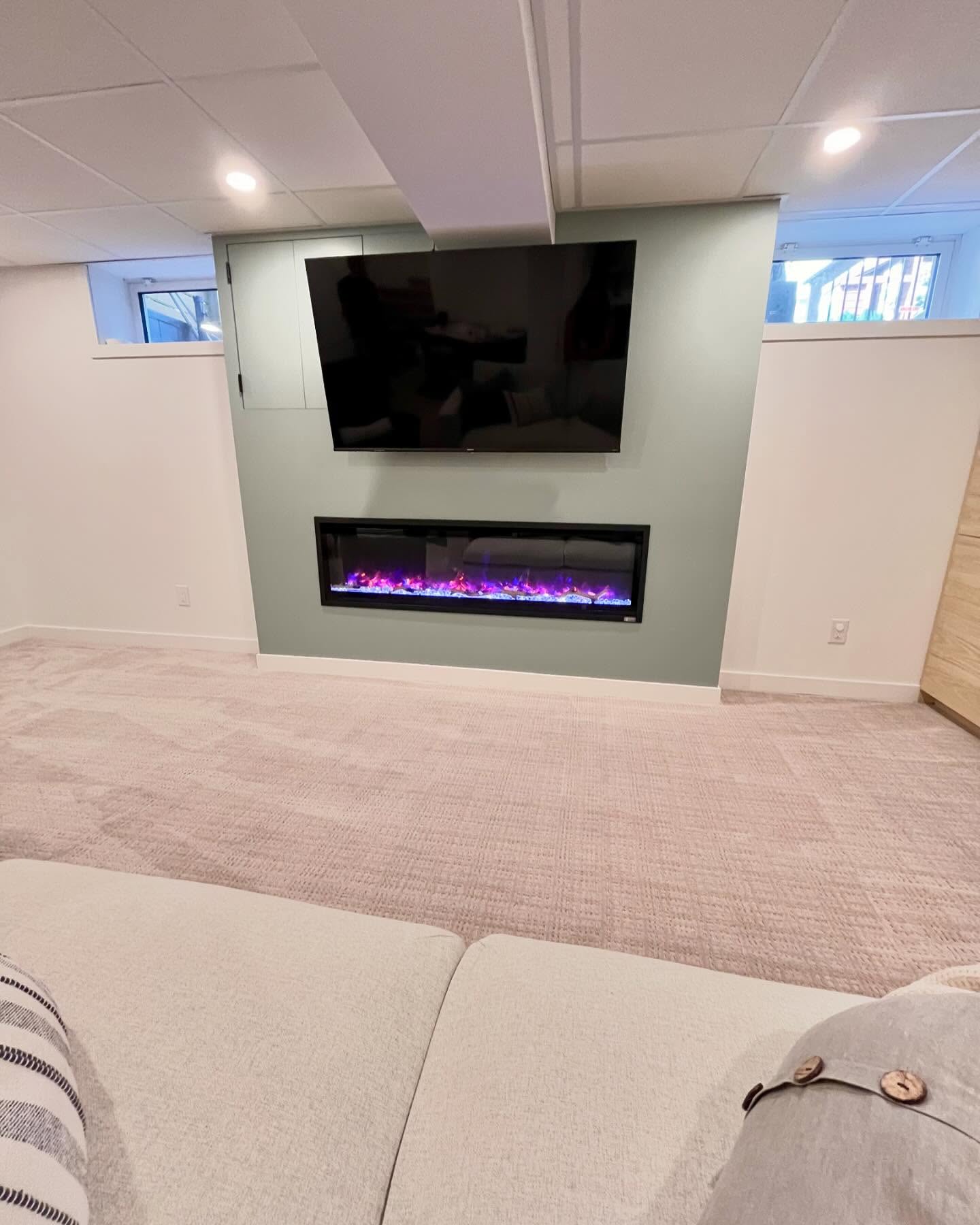Sage lounge wall with a television and linear electric fireplace