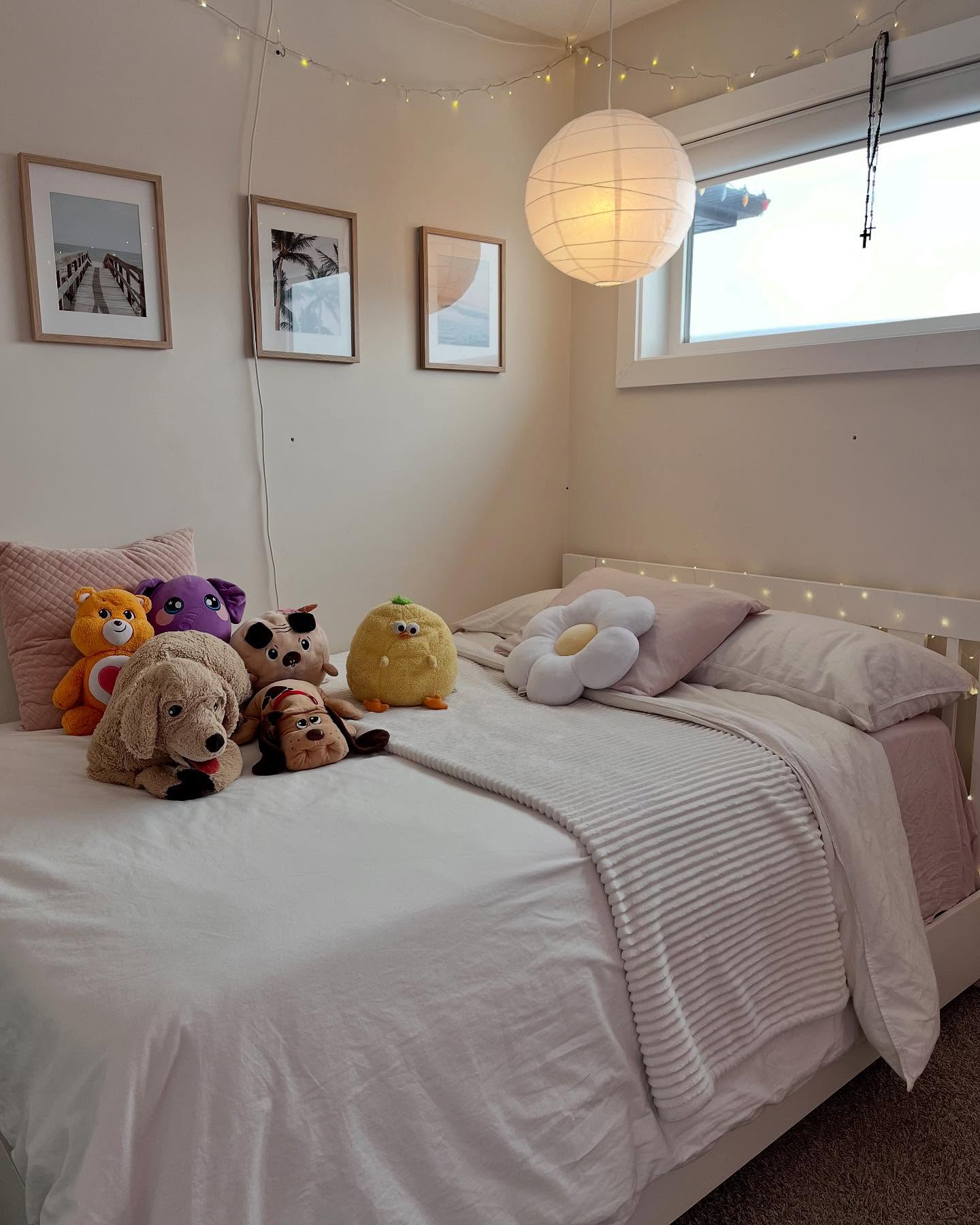 Bedroom with a white duvet, pink pillows, wood frames, and a paper lantern