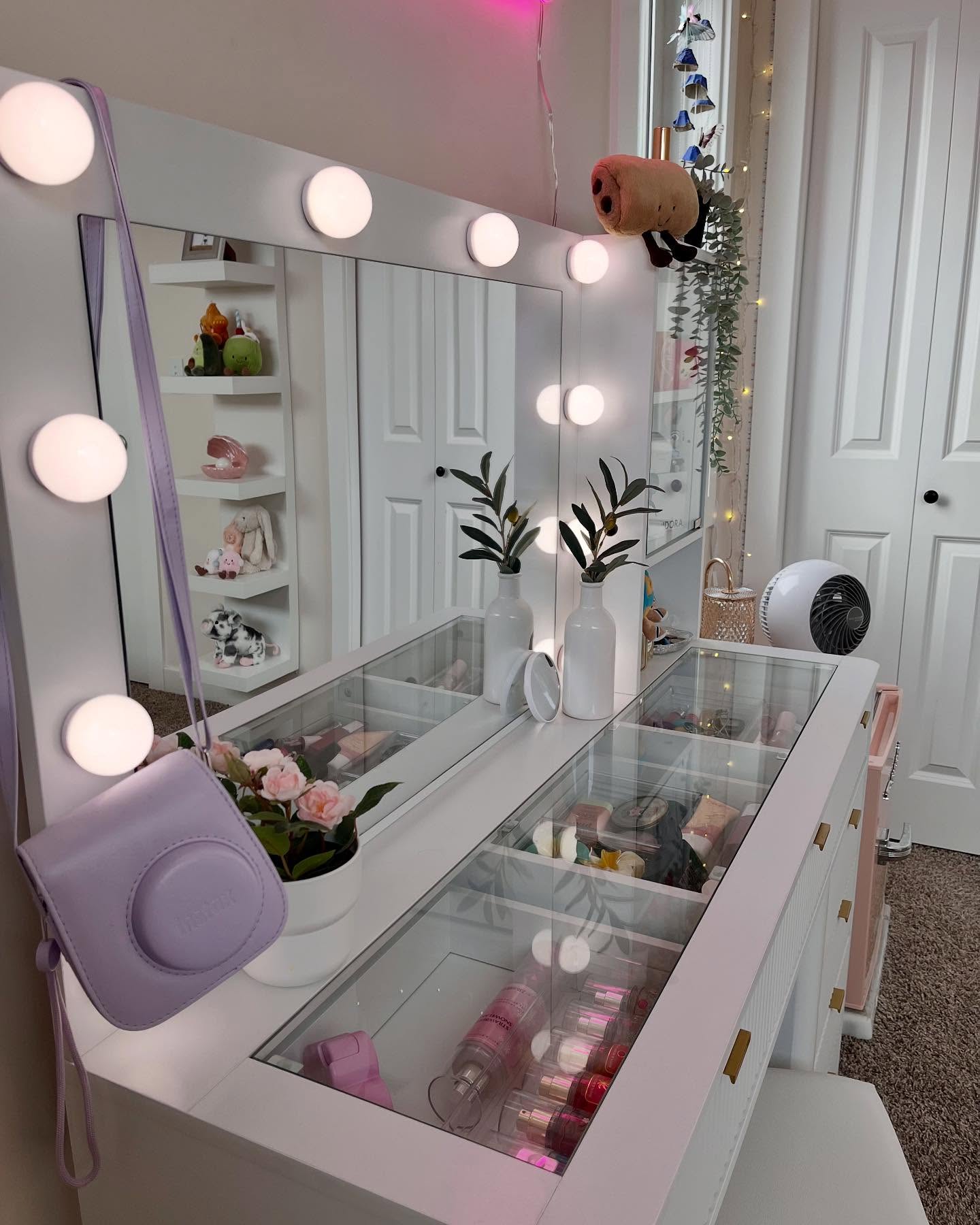 Bedroom vanity with Hollywood lights, a glass-top desk, and brass pulls