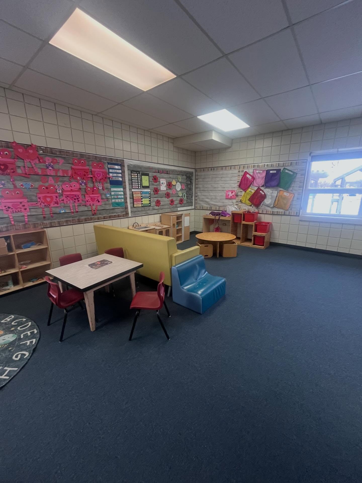Finished daycare classroom with child-size tables, storage cubbies, bulletin boards, and a window to the yard