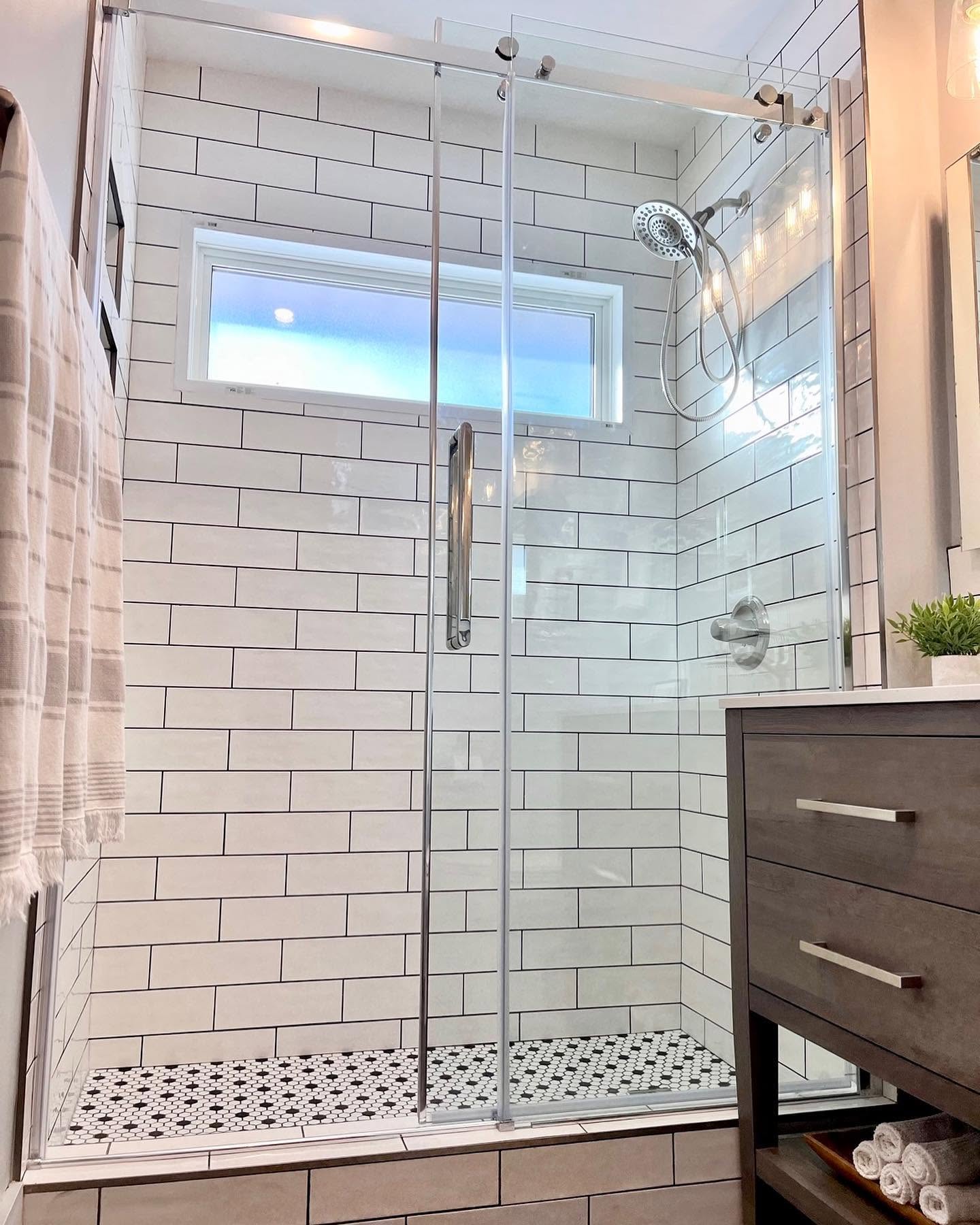 Bathroom shower with white subway tile, hex mosaic floor, and a dark wood vanity