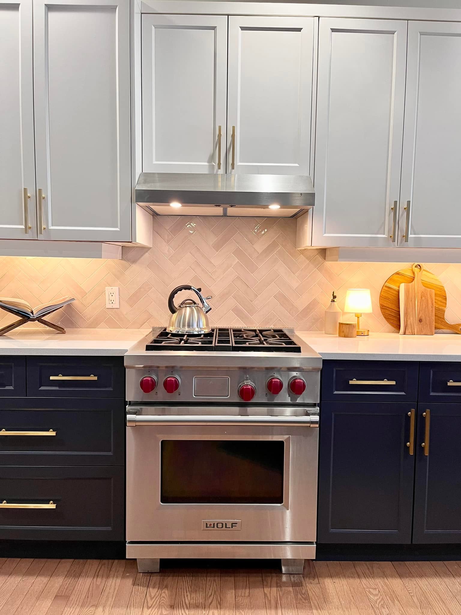 Project Lily kitchen with navy lowers, cream herringbone tile, and a Wolf range