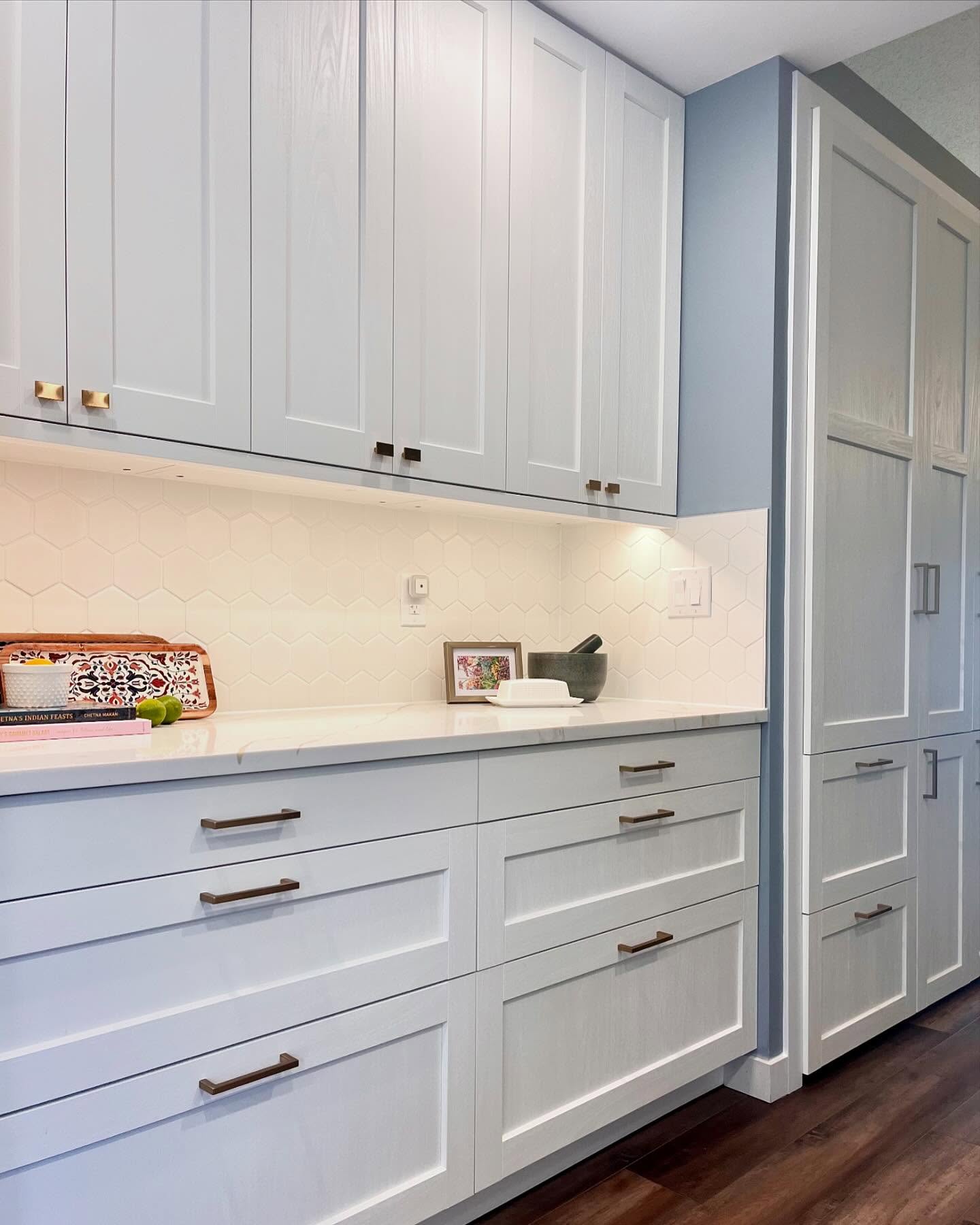 Project Daisy kitchen with white shaker cabinets, white hexagon tile, and a dusty blue wall