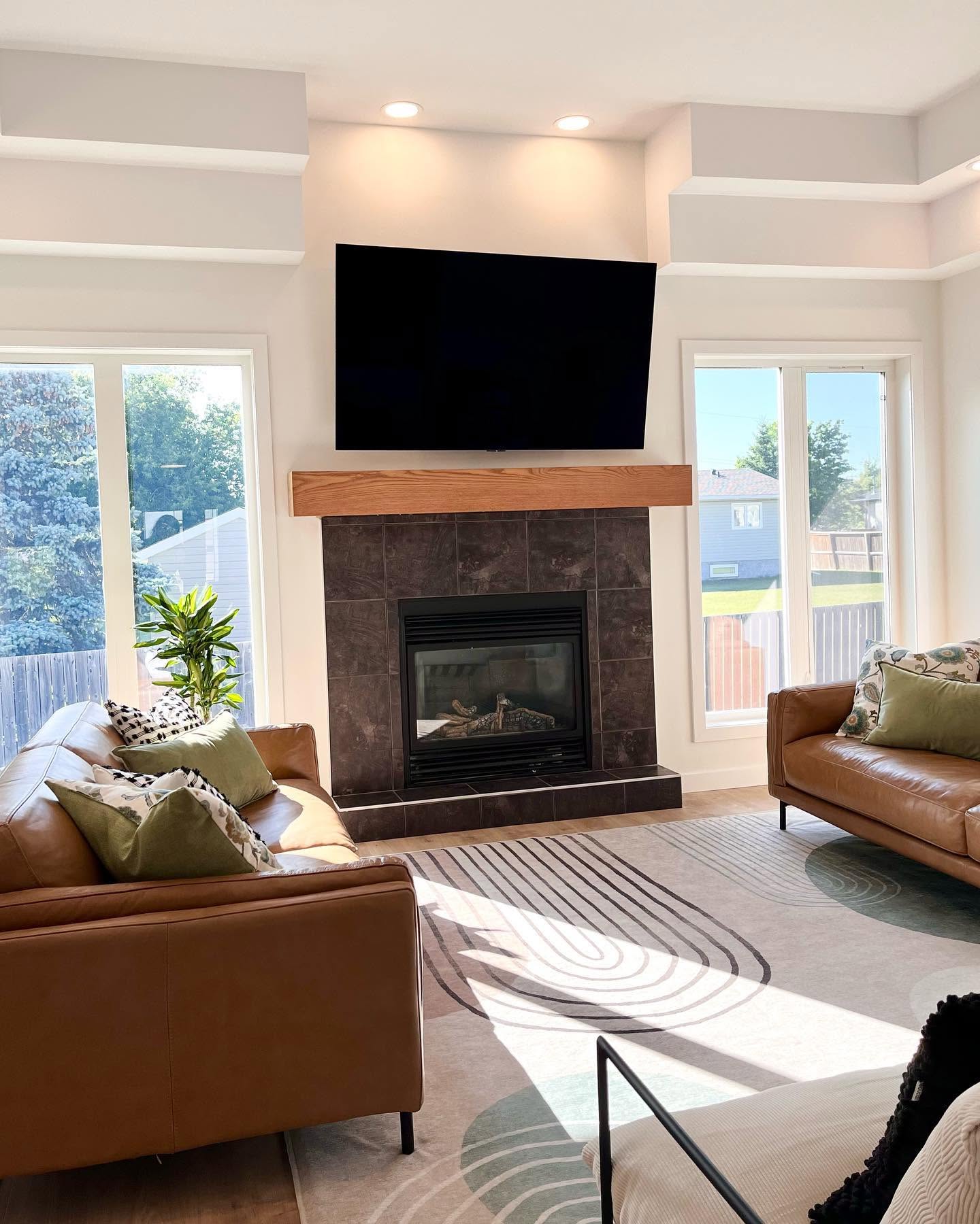 Finished living room from our Winnipeg work, with a wood mantel and leather sofas