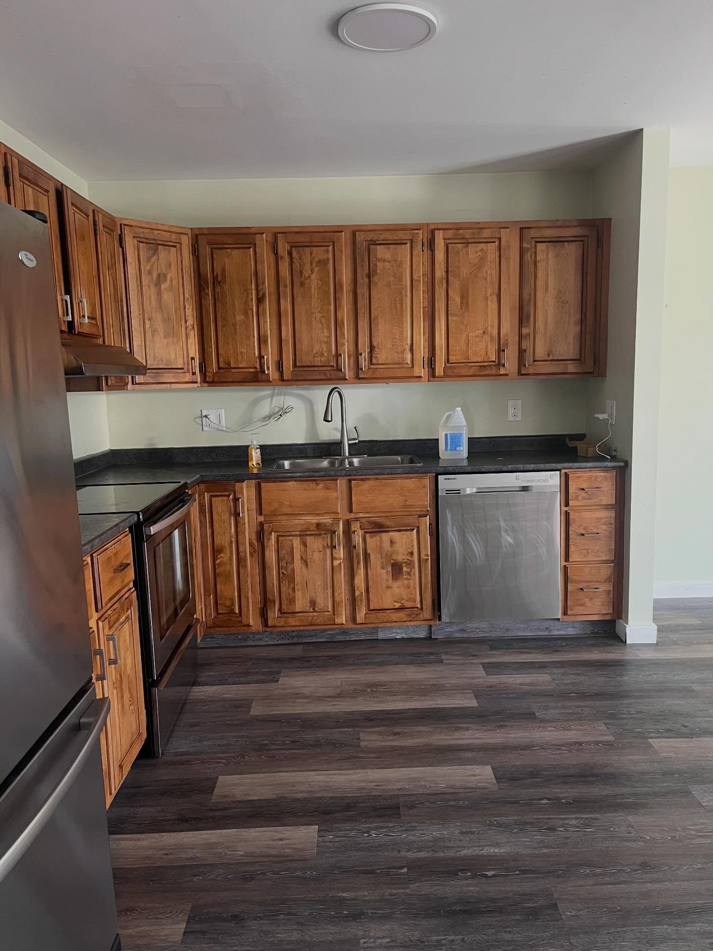 Before: oak upper cabinets, sage wall, and stainless sink and range
