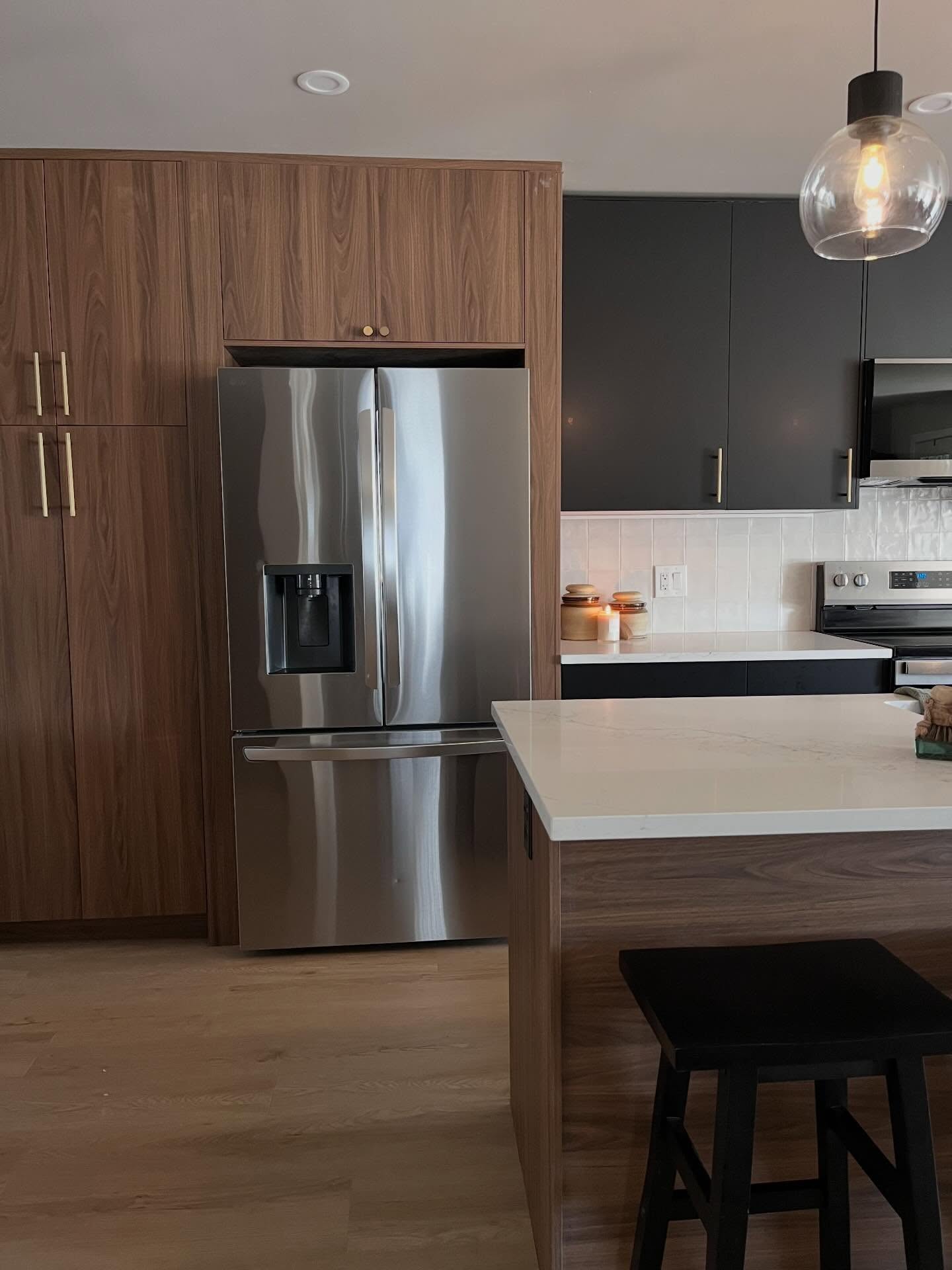 After: French-door fridge in wood-grain pantry cabinets beside charcoal uppers