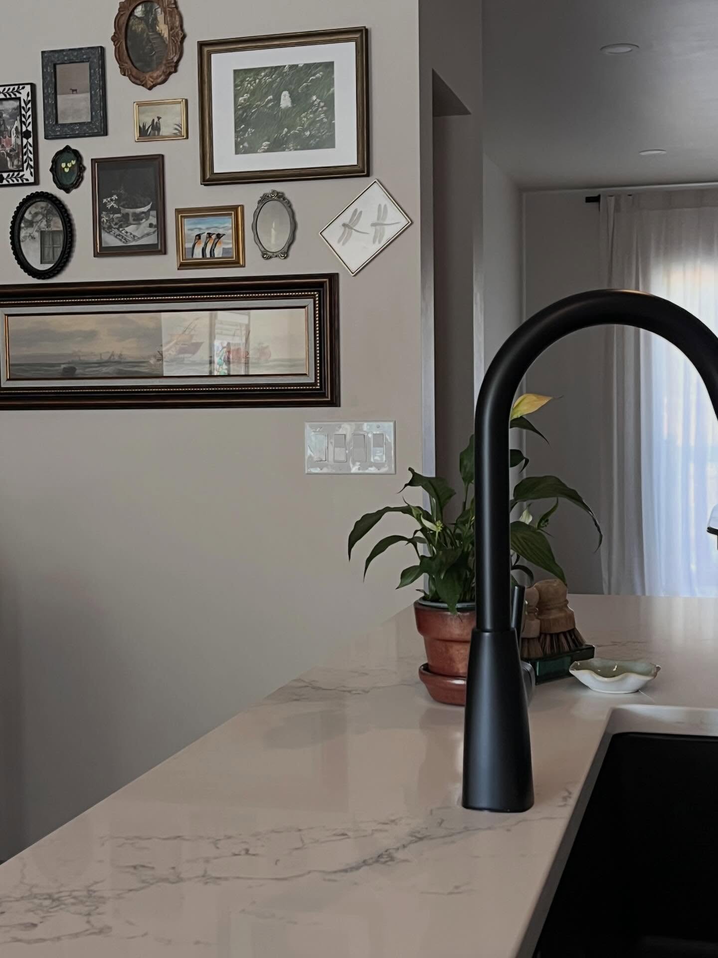 Island sink and matte black faucet with a gallery wall beyond