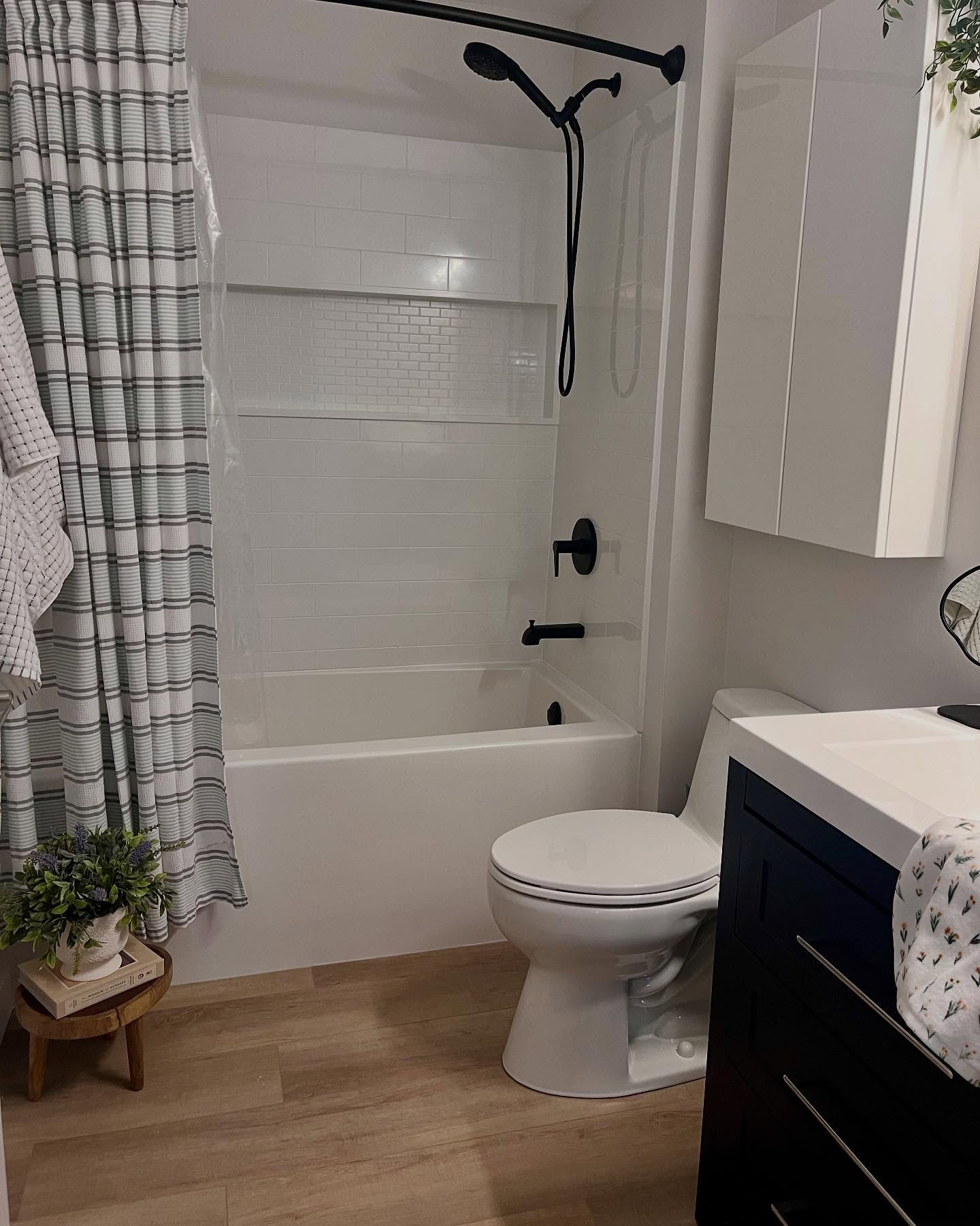 Finished Winnipeg bathroom with white tile, a navy vanity, and matte black fixtures
