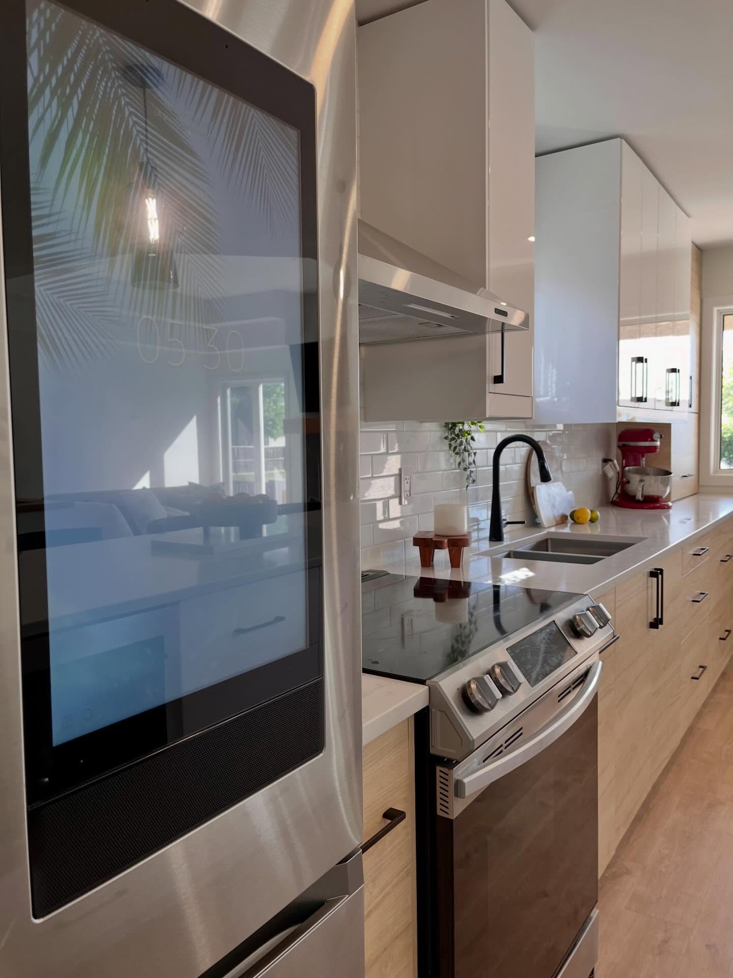 Kitchen counter run with a stainless refrigerator, wood bases, and a black faucet